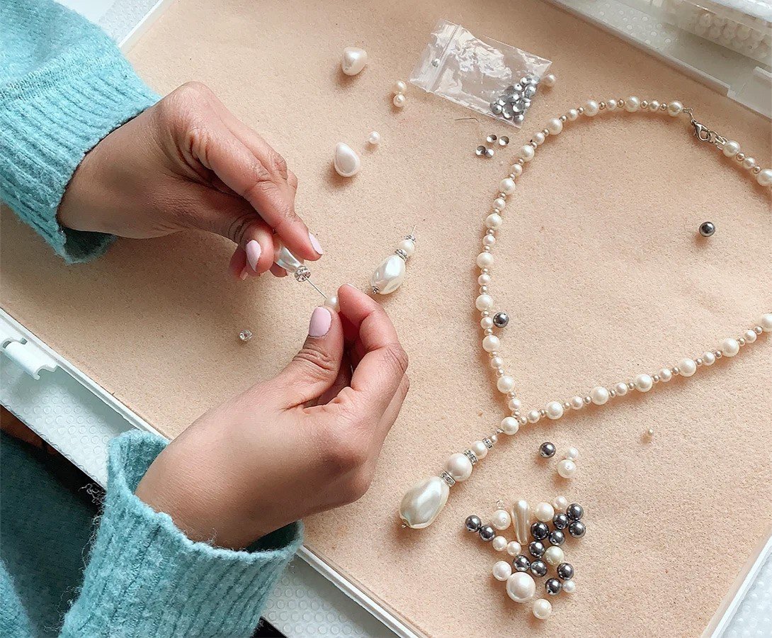 A wrist stacked with personalized letter-and-pearl beaded bracelets